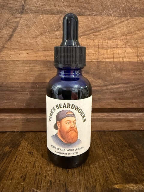 The Tink "Premium Beard Oil - Brown sugar Blend 1oz" in a blue glass bottle for male grooming.